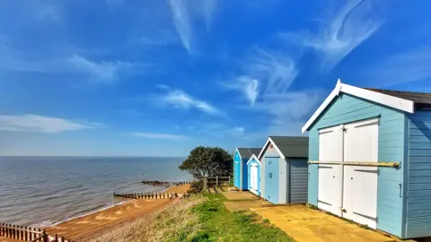 BBC Weather Watcher / MrBlueSky Beach huts next to the sea with blue skies in Felixstoe