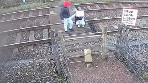 Caerphilly council CCTV shows a child squatting down on the railway track