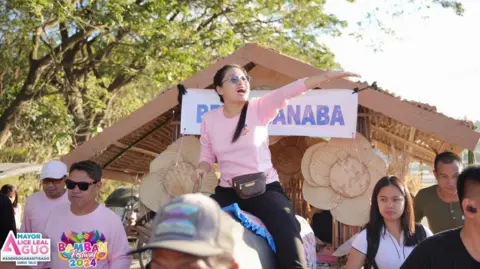 Social Media Mayor Alice Guo rides a carabao during a town fiesta