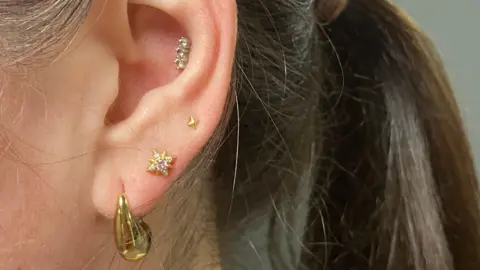 A women's ear with the lobe, seconds and inner ear pierced.