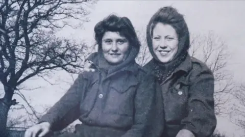 Family Photo Black and white photo of two Land Army girls in scarves and warm winter clothes.