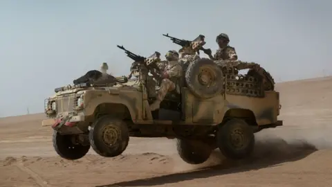 Members of a Brigade Patrol Troop, part of the Brigade Recce Force, who are an elite team within the Marine Commando Brigade, out in the northern Kuwaiti desert in their WMIK (Weapons Mount Installation Kit) Land Rover, which is based on the Land Rover Defender
