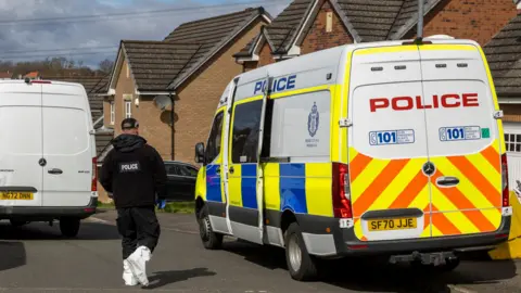 PA Media A police van and a police officer outside Murrell's home in April 2023.