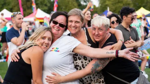 Pride in Gloucestershire Four women looking towards the camera smiling and embracing