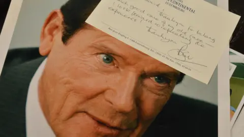 Special Auction Services A publicity photograph of Sir Roger Moore accompanied by a handwritten note from the actor thanking Dave Myers for his make-up work. The message is written on headed notepaper from the Hotel Intercontinental in Luxembourg.
