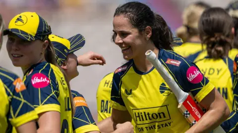 Maia Bouchier wearing a yellow Hampshire top smiles