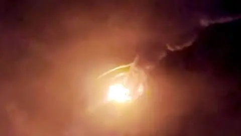 A bright light and clouds of fumes against a dark sky as a rocket explodes.