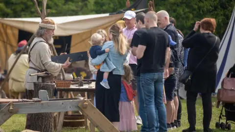 Great Ousekjarr Viking Society Crowds looking at Viking re-enactors making tools