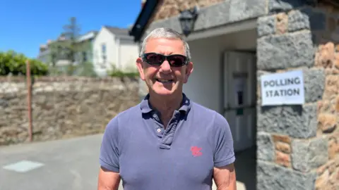 Man in blue polo short and sunglasses smiling