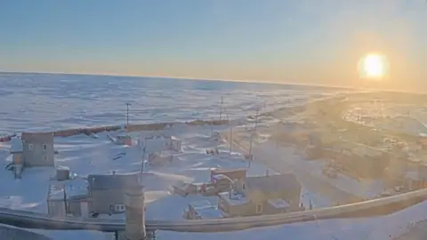Utqiagvik, Alaska is seen with the sun in the sky.