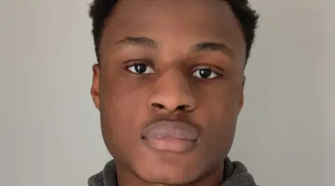 Michael Ababio, with dark hair, is looking at the camera. He is pictured in front of a grey background.