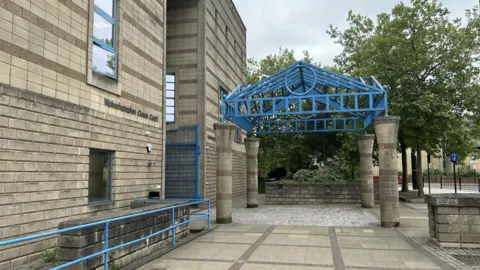 Wolverhampton Crown Court. A large grey-scale building with blue beams on top.