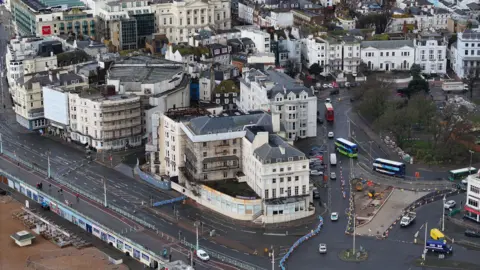 A derelict hotel next to a road with barriers blocking off the road.