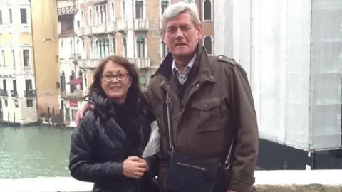 Supplied Nic and Fiona in Venice a decade ago. They are stood on a bridge with a canal behind them and buildings. 