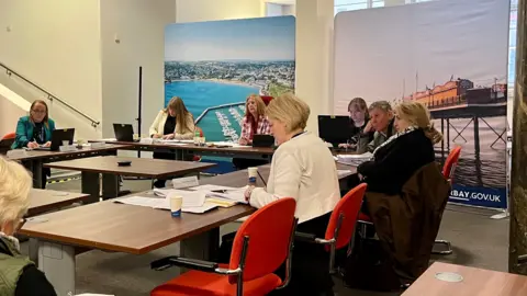 Anne-Marie Bond, in the centre in a white jacket, brought the complaint against Katya Maddison on the right in a black sweater, with other councillors in the standards committee hearing