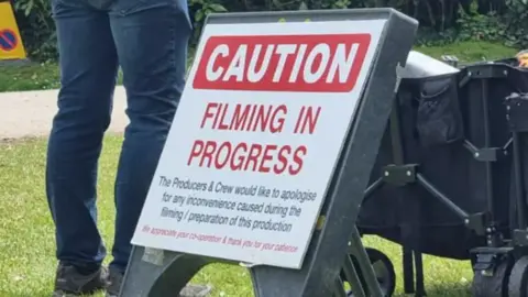 A sign which reads 'Caution: Filming in progress'.
