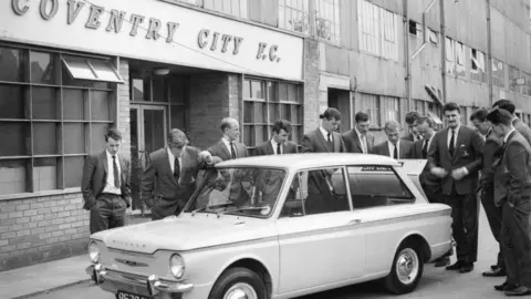 Getty Images Coventry City manager Jimmy Hill and team members check out the latest Hillman Imp at their Highfield Road ground. circa 1965.