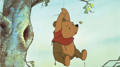 Illustration of Winnie the Pooh hanging by a rope from a tree with a perturbed look on his face