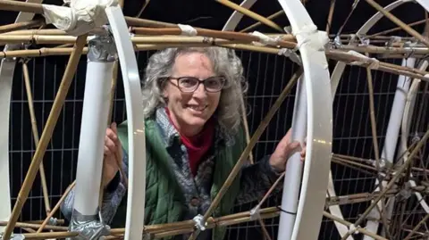 Lancashire County Council Donna Campbell standing inside a plastic and cane structure that looks similar to a giant ribcage