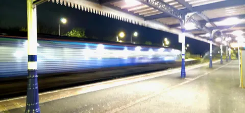 Liz White A train speeding through a railway station - it is going so fast that the image is blurred.
