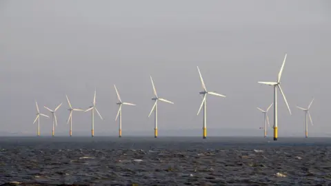 A row of eight wind turbines out at sea, with two more placed behind them.