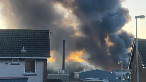 Linda Coulter Grey plumes of smoke are emerging as the result of a fire. The picture has been taken from the back of a house and it is unclear where the smoke is coming from. 