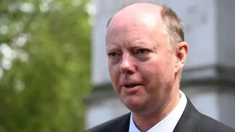 Getty Images A middle aged, balding man with dark hair at the temples. He is wearing a grey suit but pictured from the shoulders up. He is staring to the left.