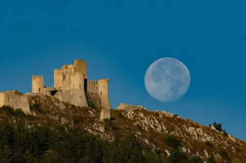 Lorenzo Di Cola/NurPhoto via Getty Images Supermoon setting behind Rocca Calascio Castle in Calascio, Italy