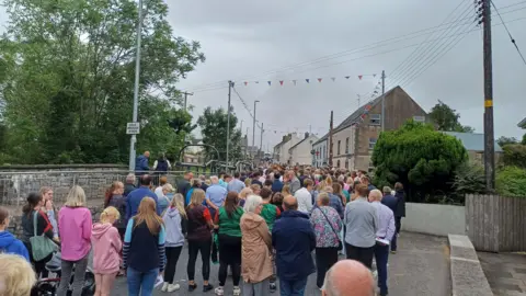 A large crowd of people on a village street. 
