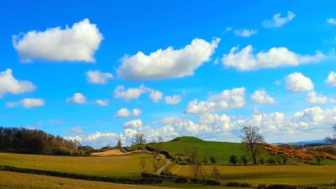 Fluffy white clouds in a blue sky above a rural landscape