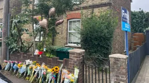 SONJA JESSUP/BBC Tributes line the wall outside a property on Bremer Road on Monday