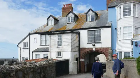 Jonathan Thacker / Geograph Rear of Guildhall Cottage - a two-storey terraced house with a third floor and dormer windows in the pitched roof. The back of the building is painted white and part of the building is clad in white timber.