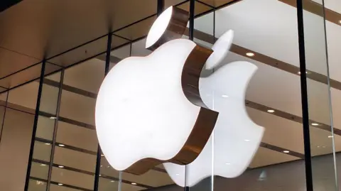 Apple logo lit up on a sign on the glass windows of a storefront in China.