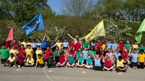 East Wichel Primary School Year 4 Swindon school with their headteacher Mrs Phillips, all wearing their house-coloured sporty school tops.