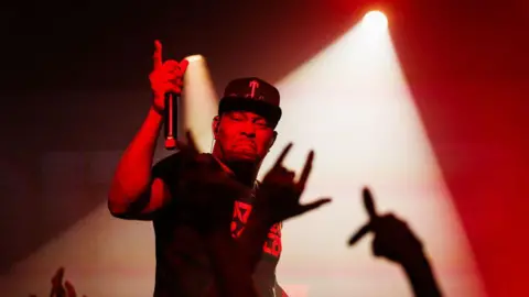 A rapper on a stage with red lights. 