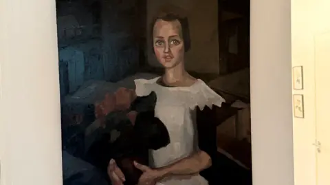 A painting believed to be Toon Kelder's 'Portrait of a Young Girl' shows a girl in a white dress with black sleeves holding what appears to be a bouquet of red flowers. She has brown hair and blue eyes and is sitting.