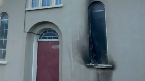 Shows scorch damage to a window and a red door 
