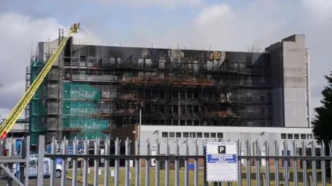 PA / Lucy North Firefighters at the scene following a fire at a block of flats in Freshwater Road in Dagenham, east London