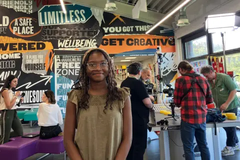 A girl smiles at the camera as she poses for a picture in a youth centre.
