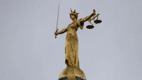Lady justice holding the scales of justice on top of a building. 