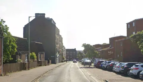 Google A residential street with houses on each side and cars parked in the street