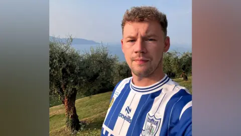 Richard Kehoe A man with fair hair looking at the camera, he is wearing a blue and white striped Newry top