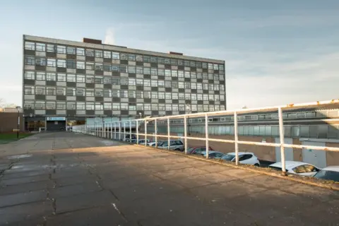 Dundee & Angus College A large six-storey building set behind a paved walkway and a car park