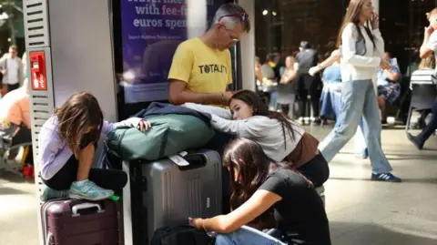 Getty Images Travelers sit by their bags as the Eurostar service experienced delays at St Pancras International Station.