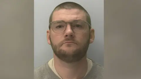 Devon and Cornwall Police A police mugshot of Mr Stubberfield. He is wearing a grey jumper and glasses. He has a beard and is staring straight at the camera. 