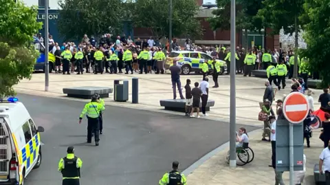 A line of police officers stand between protestors