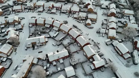 Shaun Whitmore/BBC An aerial shot of a housing estate. The rooves, roads and gardens are covered in snow. 