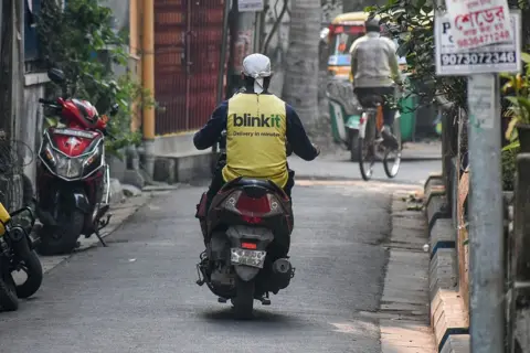 NurPhoto via Getty Images A Blinkit delivery agent wearing a yellow t-shirt is seen on the road in Kolkata, India, on January 14, 2026