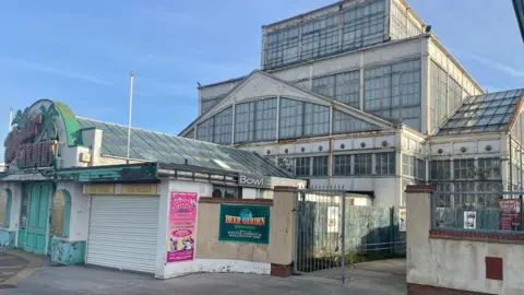 Andrew Turner/BBC Front view of the Winter Gardens that is mainly made of glass. The building has a sign on the entrance that says 'Winter Gardens'.