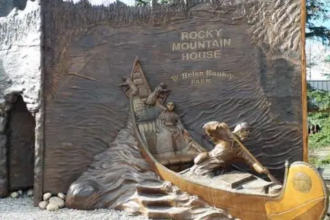 David Thompson Country A sculpture of a canoe protruding from the rockface at "David Thompson Country". It depicts David, Charlotte and some of their many children rowing through the rapids.